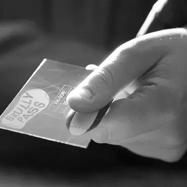 Image noir et blanc d'une main qui tend un abonnement Skully Pass
