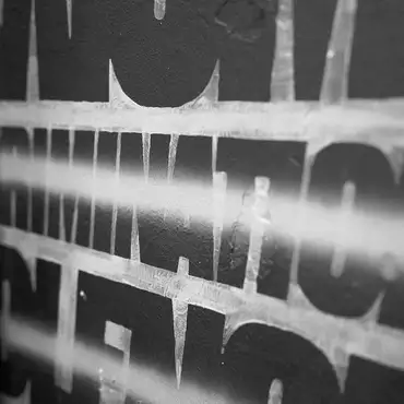 Photo en noir et blanc du mot Discrimination tracé sur un mur